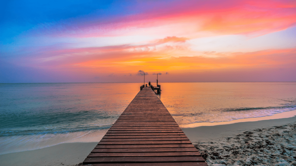 Wooden pier extending into the Caribbean Sea at sunset