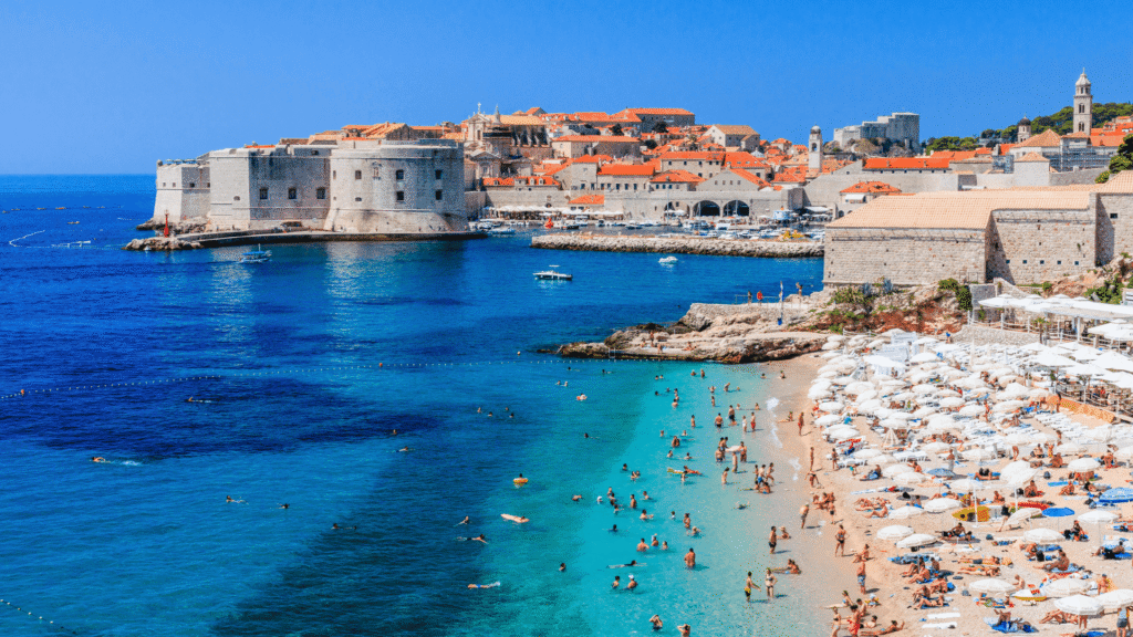 Clear Adriatic waters and beach overlooking Dubrovnik’s historic Old Town and stone city walls in Croatia